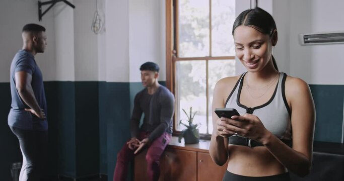 Multi ethnic young woman smiles at phone in fitness studio 
