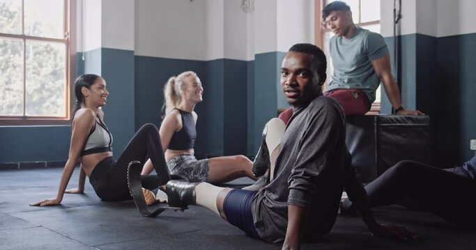 Disabled athlete sits with group of athletes in fitness studio 