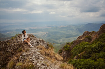 Young woman freelancer traveler working online anywhere outdoors using laptop enjoying mountain peak view. Happy female downshifter holding computer in unusual amazing view workplace at summer