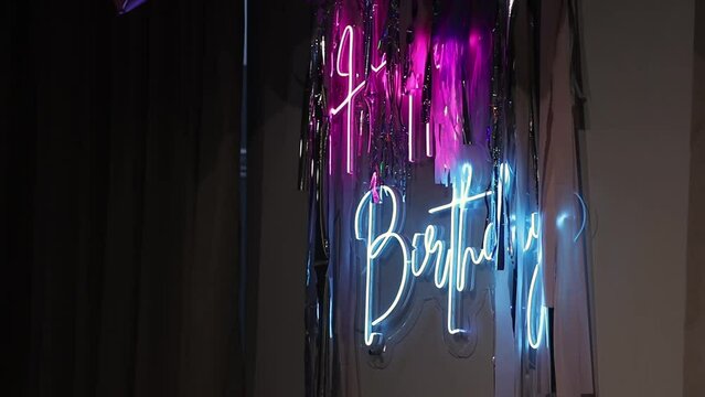 A blue and pink neon happy birthday sign. blue and pink neon sign Happy Birthday close up. Illuminated sign, blue and pink neon Happy Birthday sign illuminated in a dark room. horizontal video