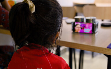 Fototapeta premium Rear view of a girl looking at a mobile phone in a cafe