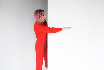 A portrait image of a woman in a red jumpsuit showing something or a copy of a place for some product