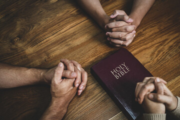 christian and prayer Group of christians holding hands praying together to believe and bible on wooden table for prayer meeting.