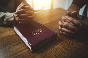 Christians and prayers Group of Christians holding hands praying for faith and Bibles on wooden table for prayer meeting. Sit and pray. - obrazy, fototapety, plakaty