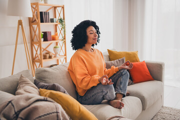 Photo portrait of lovely young lady sit sofa meditate stay calm dressed casual orange clothes cozy day light home interior living room