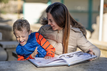 Mother and son express their complicity, while sharing the reading of a children's book in a rest area