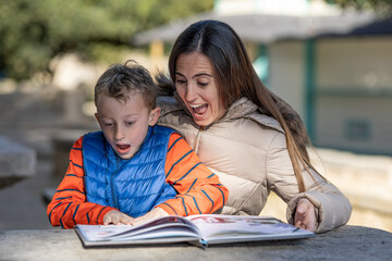 Mother and son express theis surprise at discovering the answer to a riddle, while sharing the reading of a children's book in a rest area