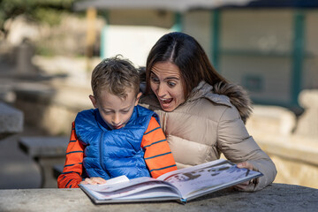 Mother and son look surprised while sharing a children's book in a rest area