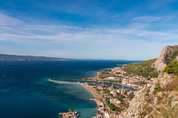 Aerial view of cetina river merging with Adriatic Sea in coastal town Omis, Split-Dalmatia, South Croatia, Europe. Idyllic spit surrounded by steep Dinara mountains. Majestic coastline of Omis Riviera