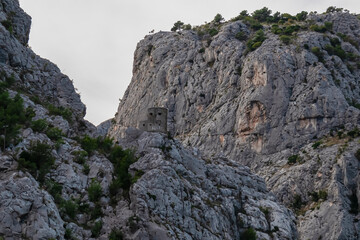 Fototapeta na wymiar Panoramic view of watch tower along Cetina river merging with Adriatic Sea in Omis, Split-Dalmatia, Croatia, Europe. Idyllic gorge surrounded by steep Dinara mountains. Majestic coastline and cliffs