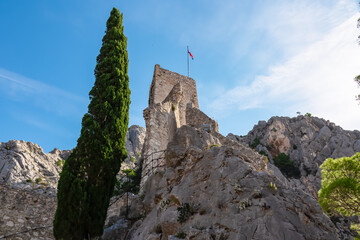 Fototapeta premium Scenic view of Mirabela Fortress (Peovica) in old town of Omis, Split-Dalmatia, South Croatia, Europe. Stone landmark surrounded by steep Dinara mountains. Ancient fort on rock formation. Tourism