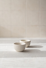 two small white ceramic saucepan on a beige background with a place for text. Japanese style. A cup for sake/tea/sauce pan.