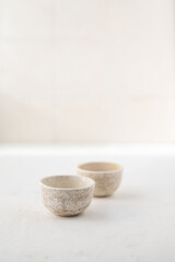 two small white ceramic saucepan on a beige background with a place for text. Japanese style. A cup for sake/tea/sauce pan.