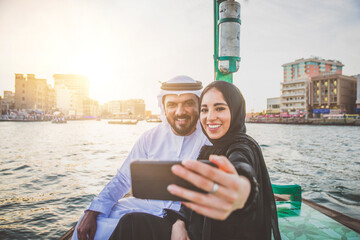 Happy couple spending time in Dubai. man and woman wearing traditional clothes taking a cruise on...