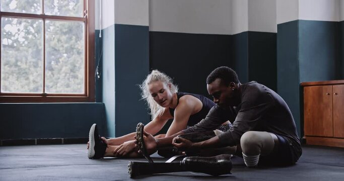 Female trainer stretches with disabled African runner before training 