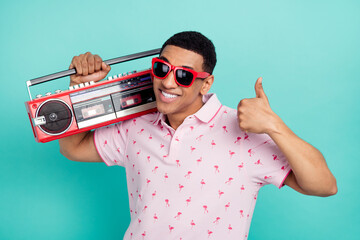 Photo of handsome guy toothy smile hold boombox demonstrate thumb up isolated on teal color background