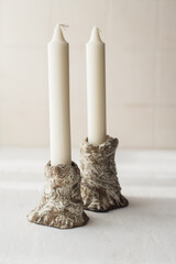two thin white candles in unusual handmade ceramic lamps