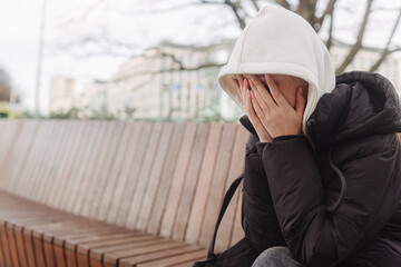 Upset and depressed girl holding smartphone and holding head. University sad student suffering from depression at high school. Lonely bullied teen.