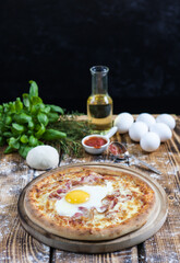 Rustic wooden table with homemade rye flour pizza and the ingredients from which it is made from the back.
