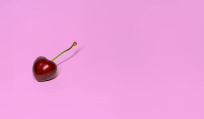 red cherry with a glossy surface and a green stem, its sweet ripeness suggested by its deep red color - 764226399