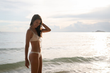 A woman is walking on the beach, enjoying the ocean view.