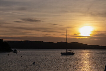 Silhouette of sailing boat during romantic sunset in idyllic Kvarner Bay in Medulin, Croatia, Europe. Calm bay of Adriatic Mediterranean Sea. Tranquil peaceful scene. Travel destination in summer