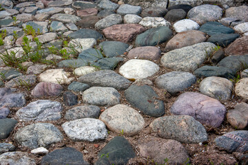 Top view of the cobblestone pavement. Stones pavement after the rain. The road is paved with rounded stones.
