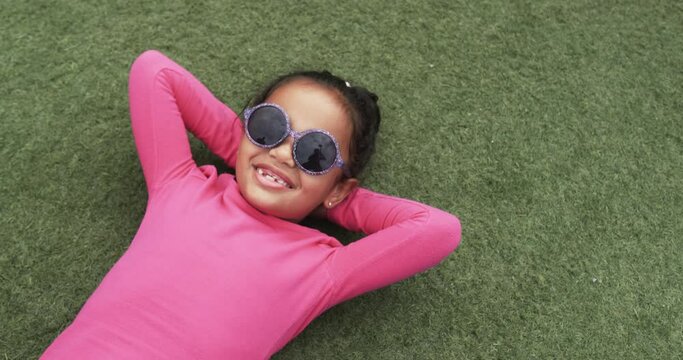 A young biracial student is lying on the grass, smiling widely