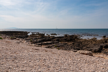 Idyllic rocky beach in tourist coastal town Medulin, Istria peninsula, Croatia, Europe. Panoramic view of rugged coastline of Kvarner Gulf in Adriatic Mediterranean Sea in summer. Travel destination