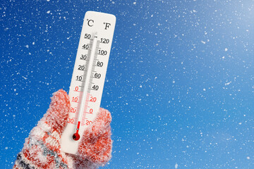 Celsius and fahrenheit scale thermometer in hand. Ambient temperature minus 27 degrees. - obrazy, fototapety, plakaty