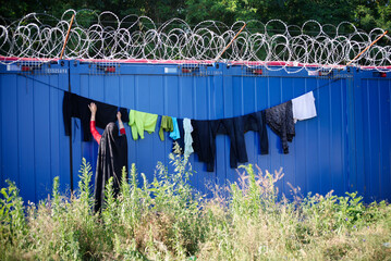 Washed clothes drying below barbed wire. Challenging living conditions in an improvised transit...
