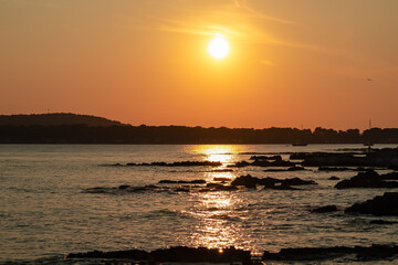 Beautiful sunset at rocky beach in coastal town Medulin, Istria peninsula, Croatia, Europe. Romantic view of rugged coastline Kvarner Gulf in Adriatic Mediterranean Sea in tranquil summer. Tranquility
