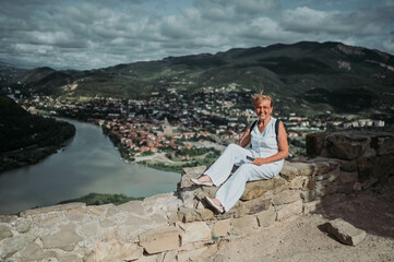 Mature woman tourist takes pictures on observation deck confluence of two rivers Aragvi and Kura,...