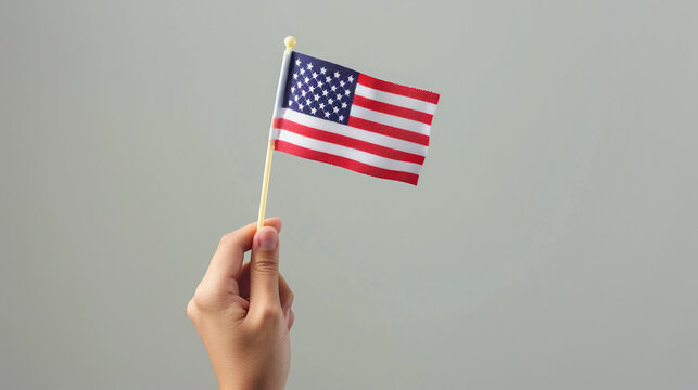 Hand holding USA flag on gray background. 4th of July independence day banner with copy space