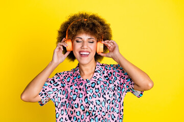 Photo of funky dreamy woman wear animal print shirt closed eyes enjoying music headphones isolated yellow color background