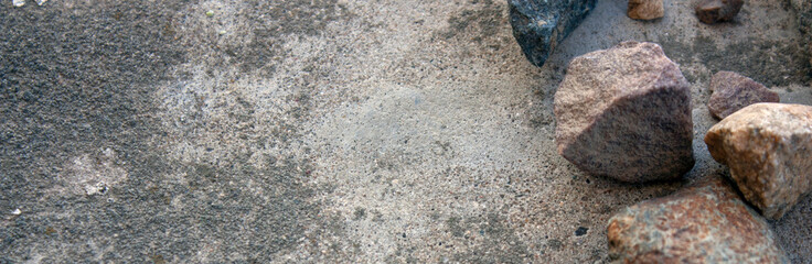 Granite stones lie on a cement screed. Large granite stones lie chaotically, top view. Granite stones next to each other.