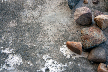 Granite stones lie on a cement screed. Large granite stones lie chaotically, top view. Granite stones next to each other.