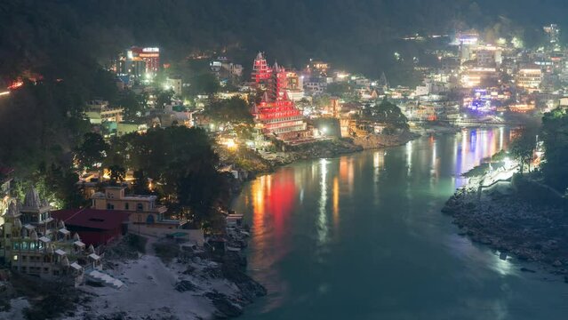 Dusk to night, zoom out timelapse showing Hindu temples on the banks of the sacred Ganges river in Rishikesh, Uttarakhand, India. 