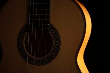 Obraz premium Classical Spanish flamenco guitar close up, dramatically lit isolated on black background with copy space.