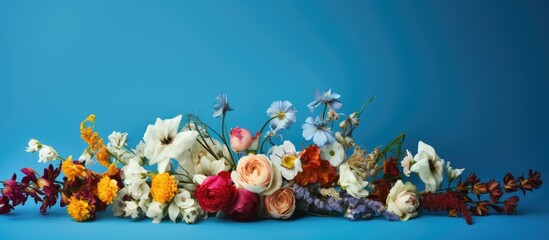 Fototapeta na wymiar A multicolored bouquet of wilting flowers on a blue surface