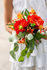 Flower girl in white dress holding colorful bouquet of flowers