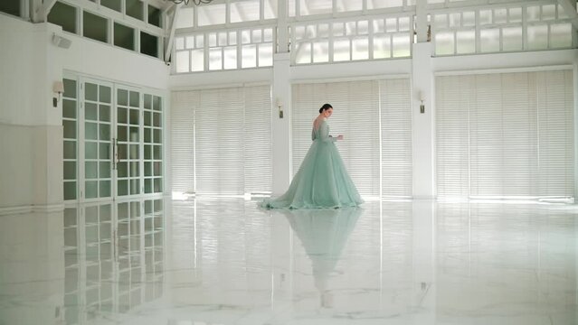 Elegant ballerina dancing in a bright, spacious hall with large windows and reflective floor.