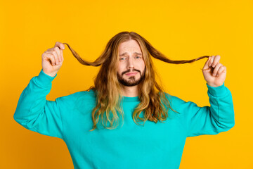 Portrait of disappointed person sullen face arms hold split hair ends isolated on yellow color...