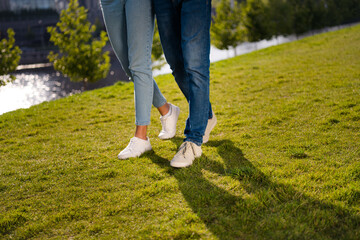 Cropped photo of two partners legs shadow footwear ad walking green grass fresh air free time...