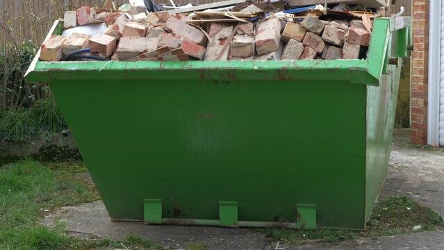 A dumpster or skip, full to overflowing with bricks and other building waste from a house renovation.