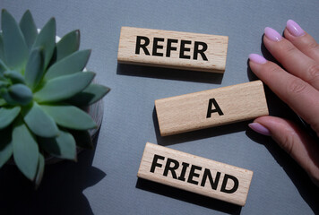 Refer a Friend symbol. Concept words Refer a Friend on wooden blocks. Beautiful grey background...