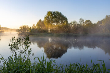 Naklejka na ściany i meble Colorful spring dawn by the river, fabulous fog