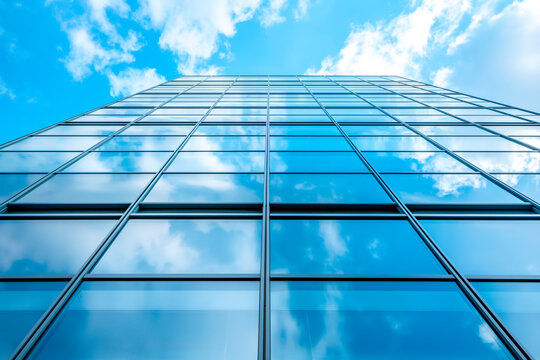 Modern office building with blue sky, and glass facades. Economy, finances, business activity concept, Bottom-up view, blurred image