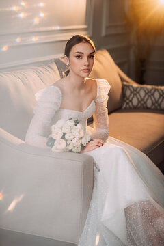 The image features a woman in a white wedding dress sitting on a couch indoors 6559.