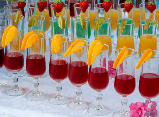 Crystal glasses with aperitifs of different tastes and colors. Fruit on the edge of the glass as an...